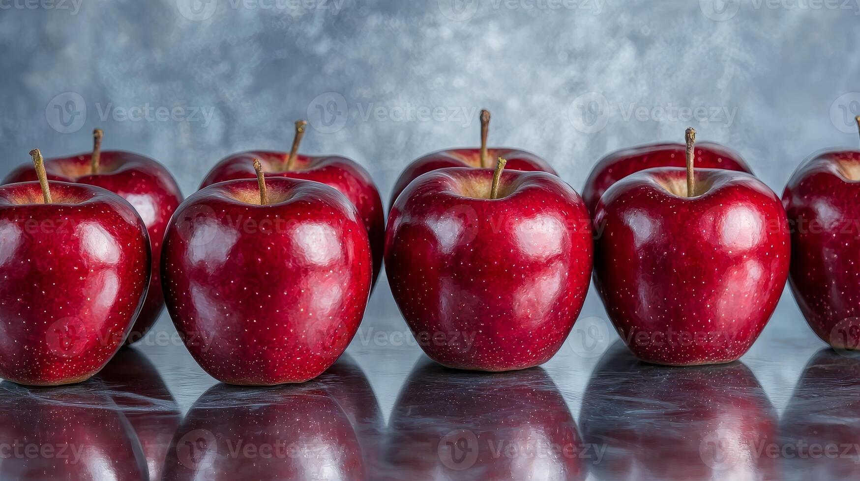Fresh red apples arranged in a line on a reflective surface. photo