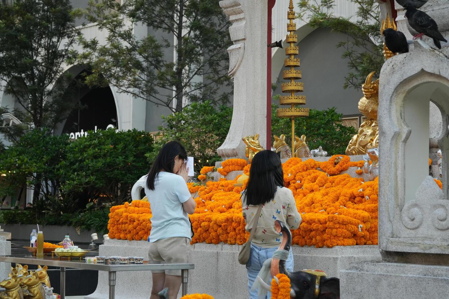 Bangkok, Thailand, 2024 - woman prays at a spirit house on shrine, The Buddhist nation combines animism in the practise of folk religion unique to the region photo