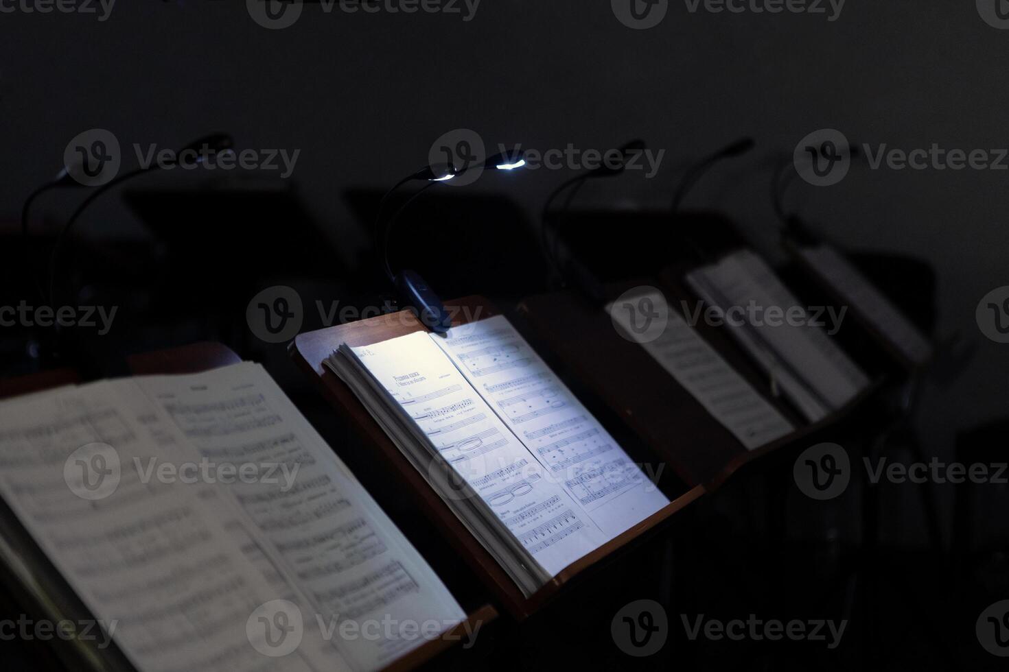 Music stands with musical notes in the rehearsal room. The music stands have lanterns attached to them for lighting. photo