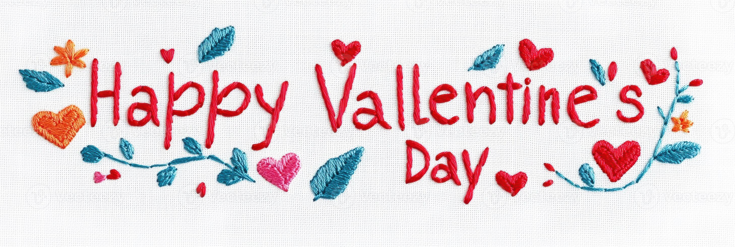 Stylish embroidered design showcasing the words Happy Valentines Day in vibrant colors on soft white fabric background with floral accents photo