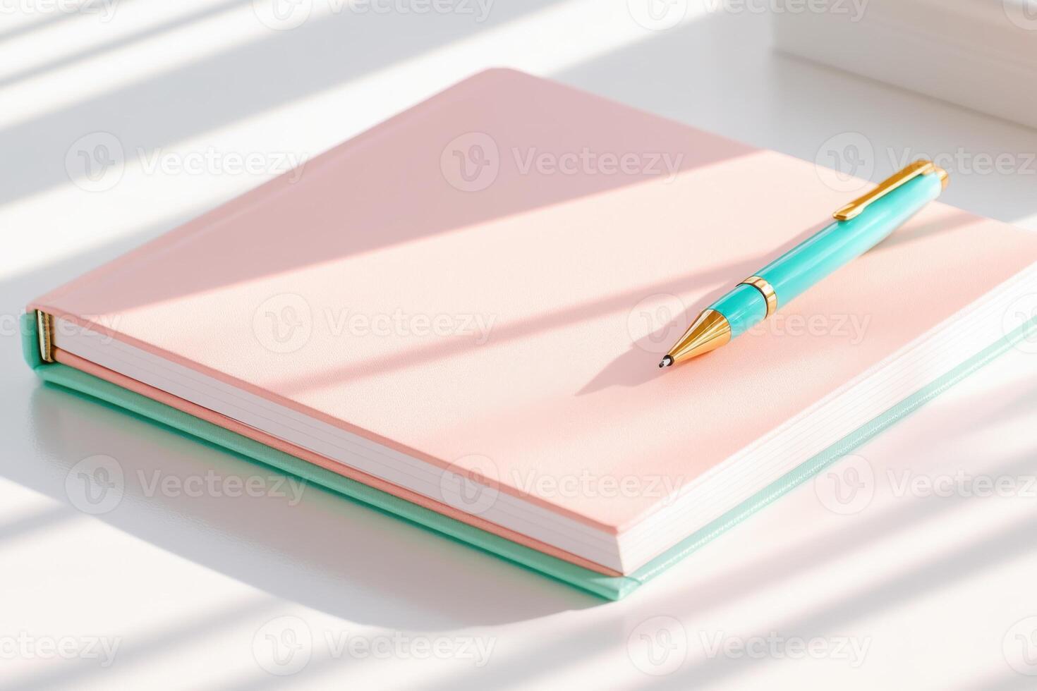 Open notebook with pastel pink pages and mint accents placed on a white desk with a teal pen ready for writing notes and ideas photo