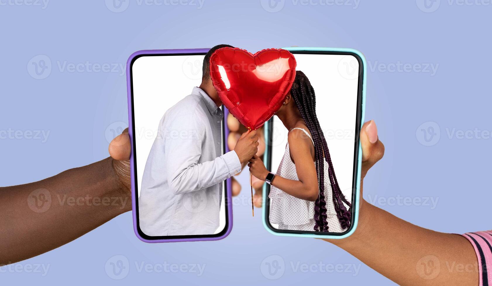 Two hands hold smartphones displaying a couple kissing while a heart balloon floats between them. This representation of digital love captures their intimate connection through messaging. photo