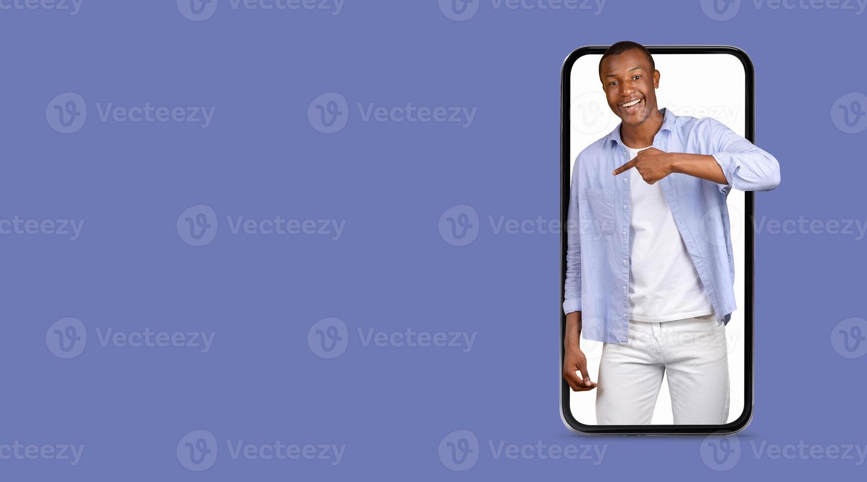 A person is happily pointing at a smartphone with a large screen, showcasing the ease of communication and social media interaction through advanced technology. The background features an empty space. photo