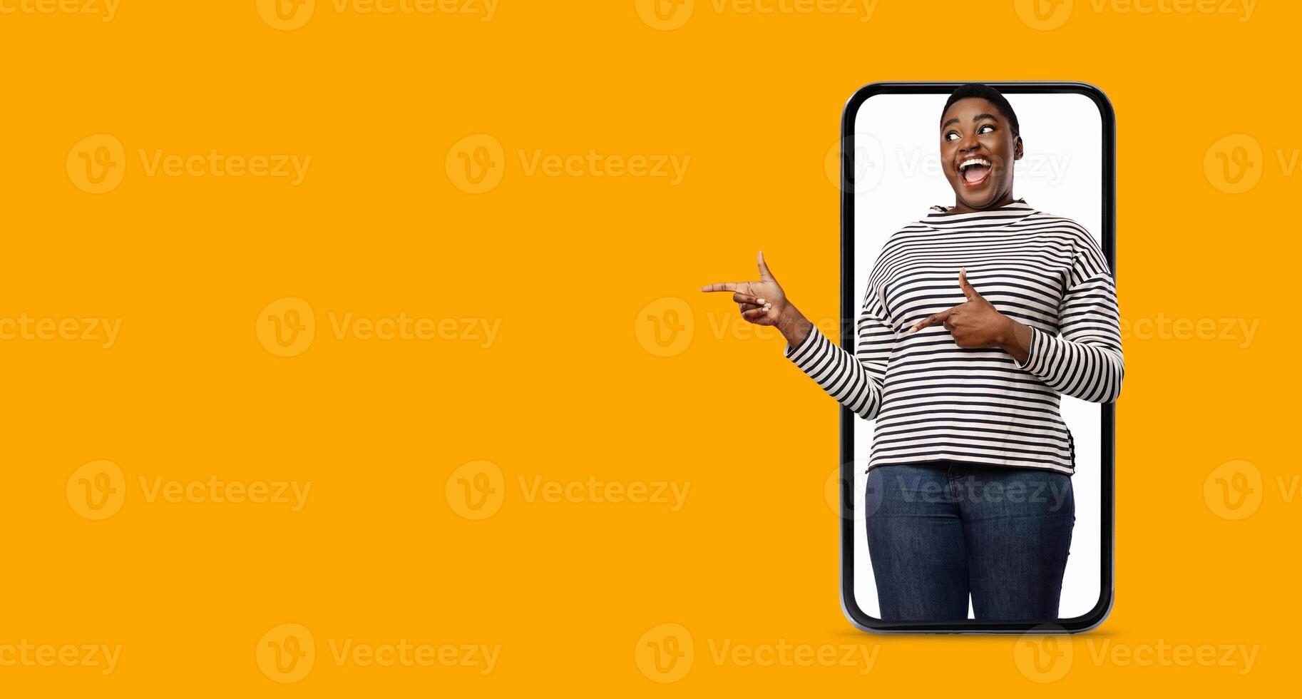 A person is playfully pointing while standing in front of a large smartphone display. The bright background enhances the cheerful communication, reflecting modern technology use. photo