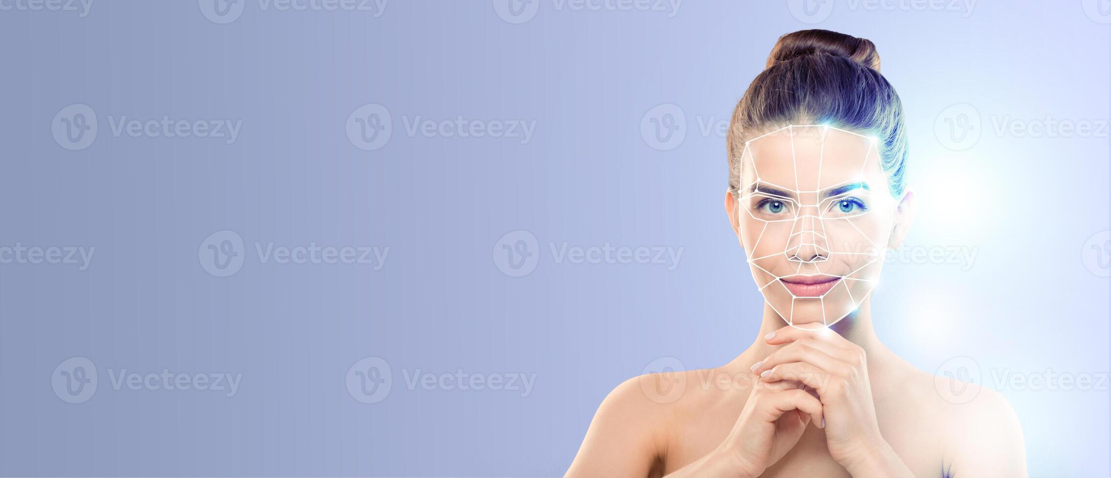 A young woman demonstrates facial recognition technology by aligning her face for identification. The backdrop is a smooth blue gradient, emphasizing the tech in an isolated setting. photo