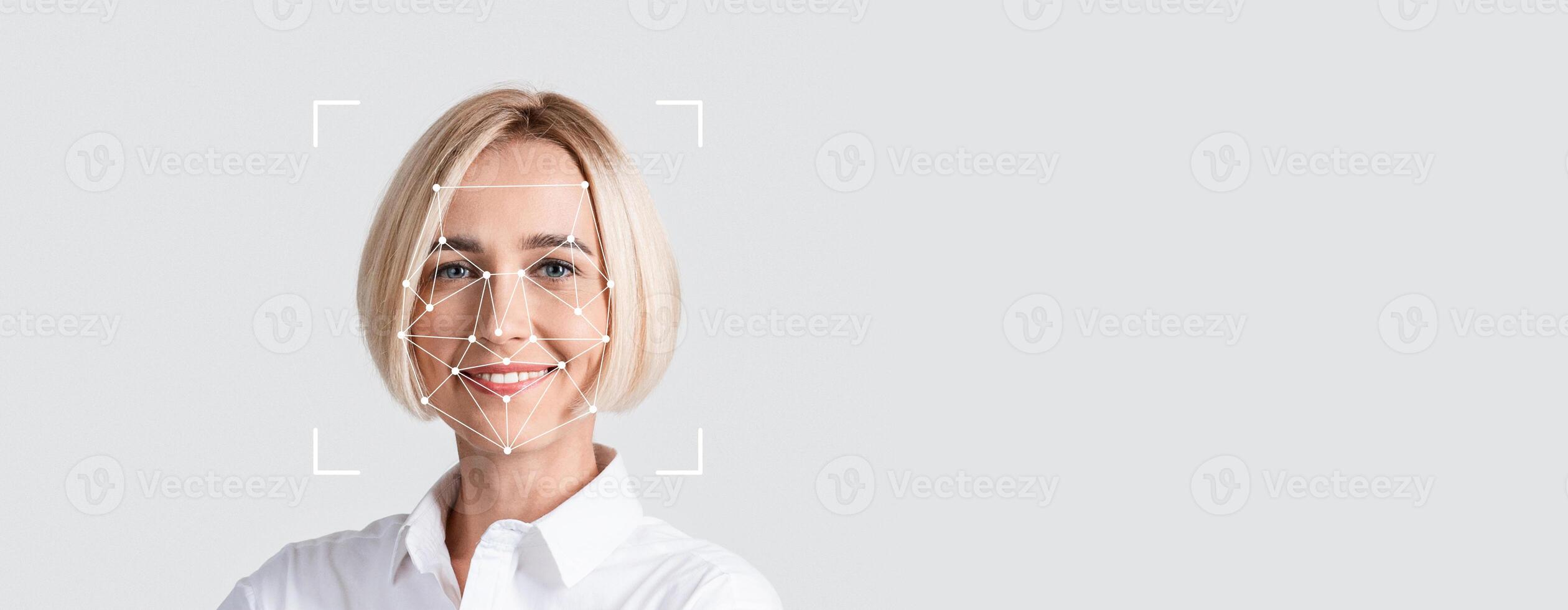 A person is engaged in facial recognition technology, smiling toward the camera against a blank background. The focus is on their facial features, illustrating identification processes. photo