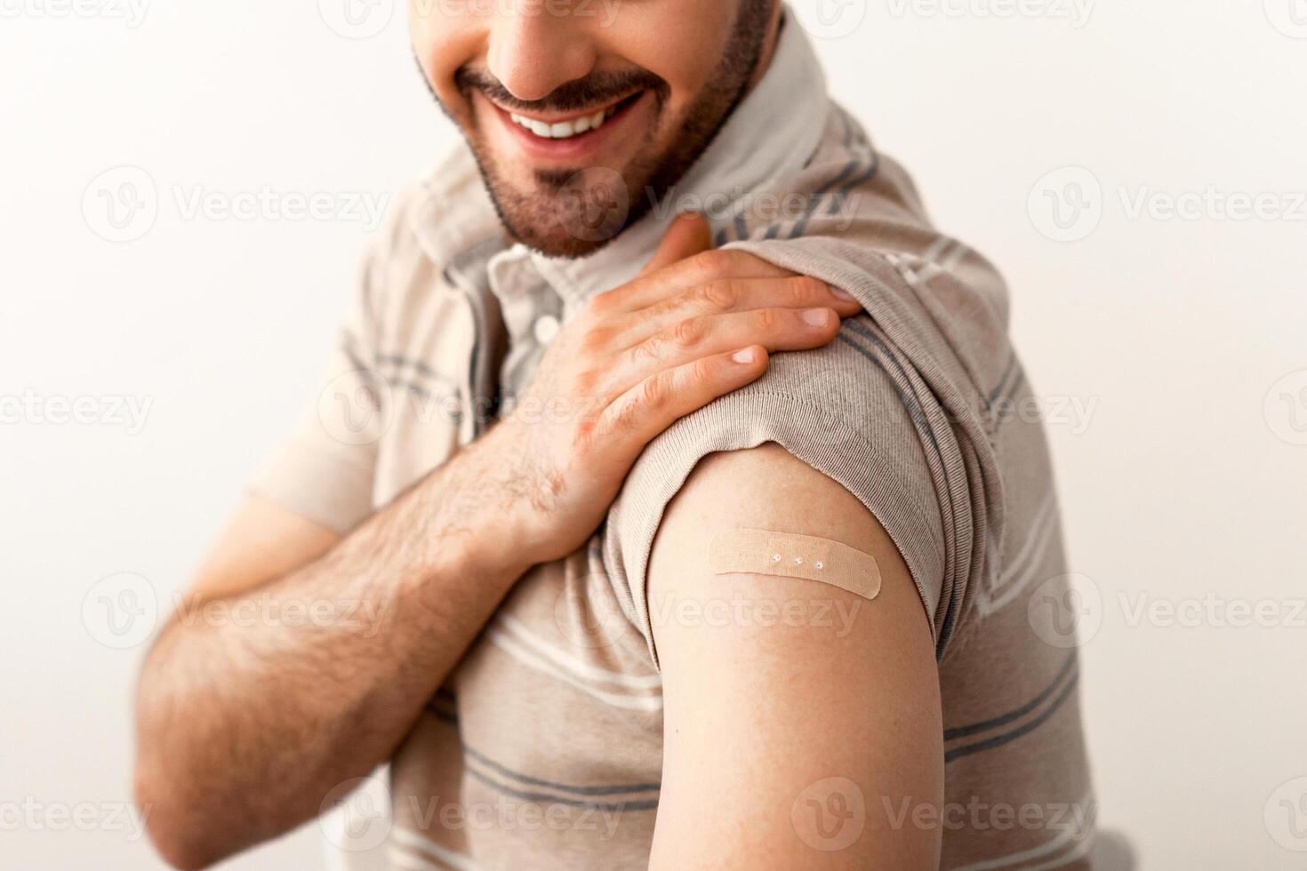 Healthcare And Inoculation Concept. Portrait Of Smiling Jewish Male Patient Showing Vaccinated Arm With Plaster On Shoulder After Coronavirus Vaccination, Looking At Hand. Antiviral Vaccine photo