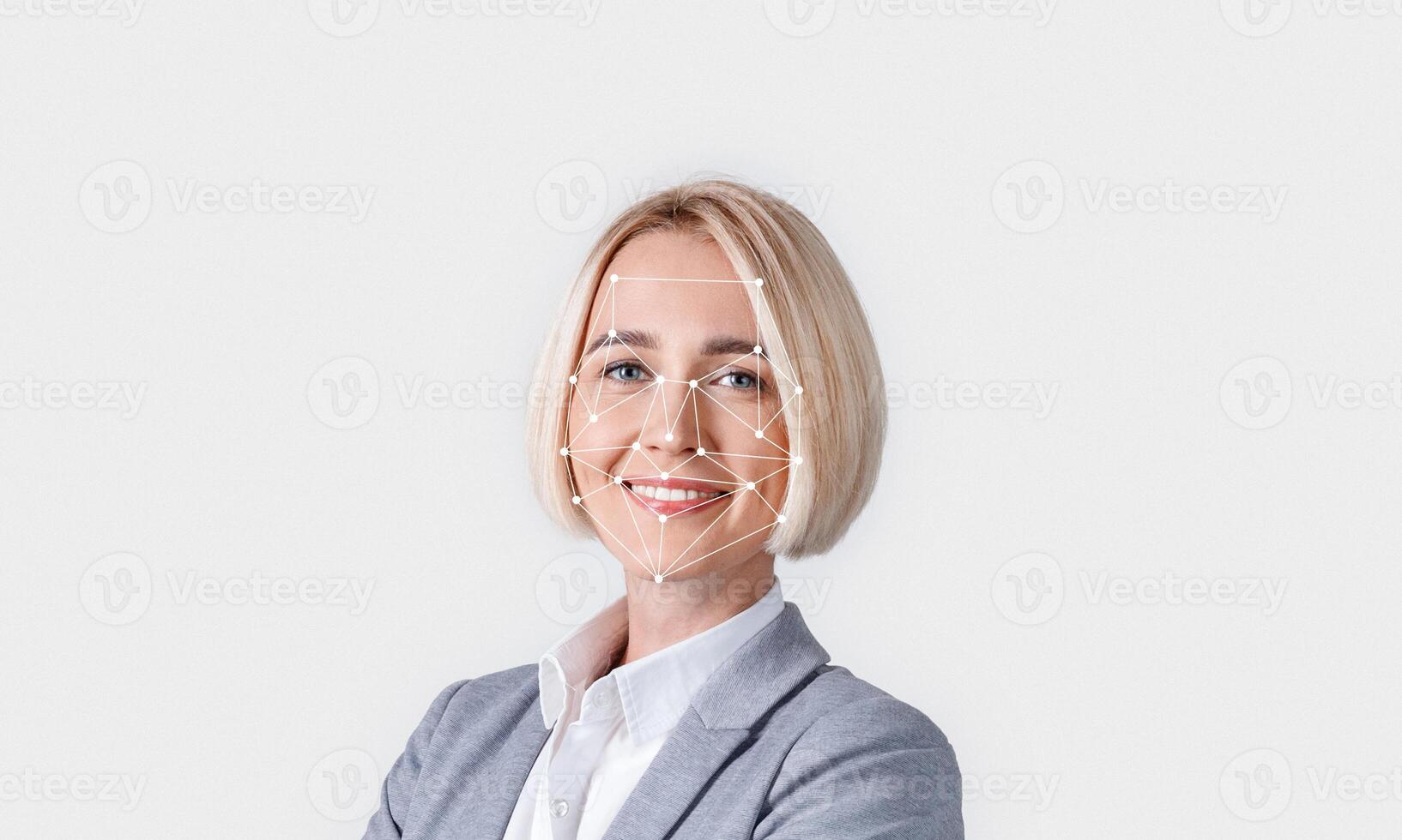 A person with short blonde hair is smiling confidently in a professional outfit. A digital overlay of facial recognition technology is displayed, indicating identification efforts. photo