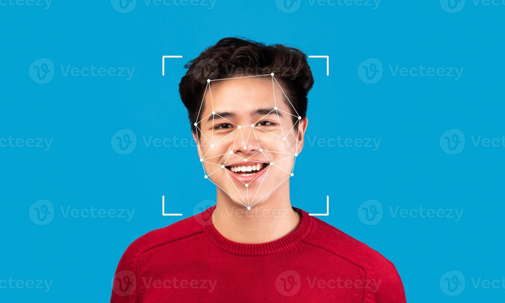 A young man with a cheerful expression poses against a vibrant blue background. Facial recognition markers highlight his features, showcasing advanced identification technology in use. photo
