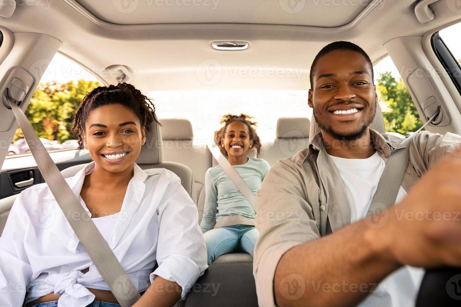 Car Sales. Cheerful Black Family Posing Sitting In New Automobile, Smiling To Camera Driving Traveling By Auto On Weekend. Road Trip Adventure Concept. Selective Focus photo