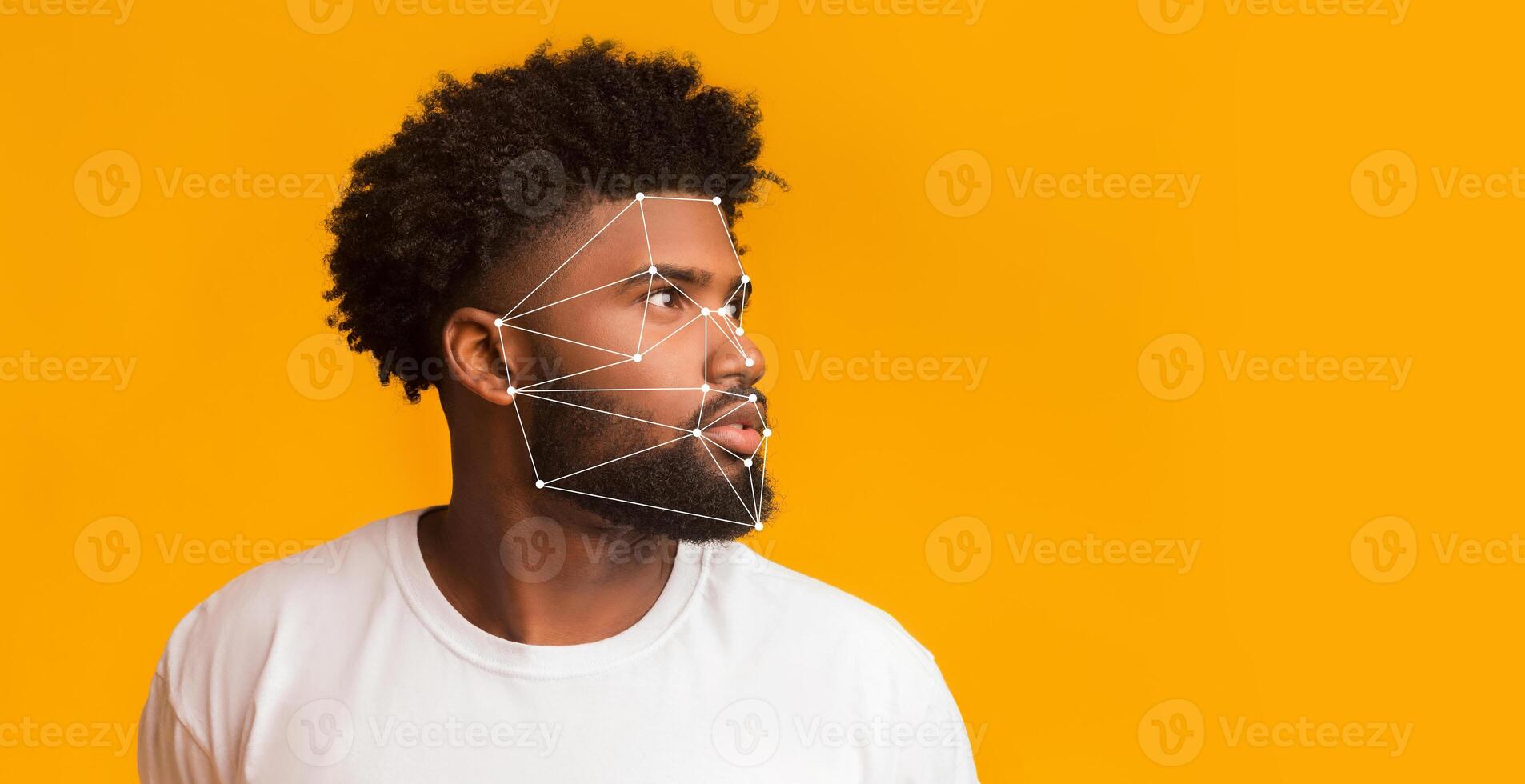 A man gazes thoughtfully to the side, showcasing facial recognition patterns mapped on his face. The bright yellow background enhances the focus on technology's role in identification. photo