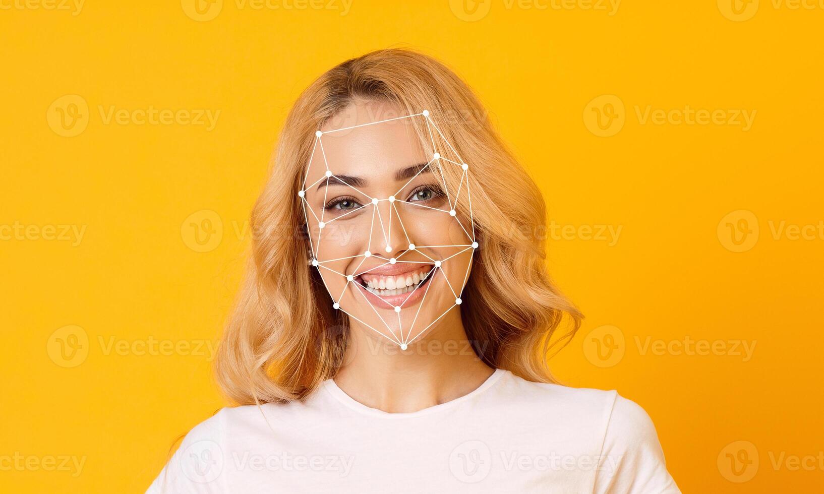 A woman with blonde hair smiles joyfully while facial recognition technology overlays a geometric pattern on her face. The bright yellow background enhances her cheerful expression. photo