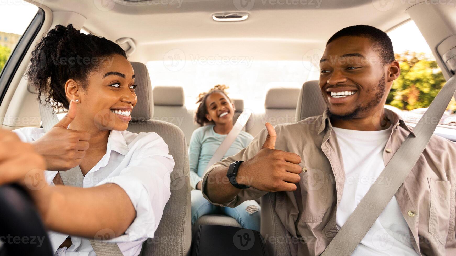 Cheerful African Family Of Three Driving Riding New Car Gesturing Like Approving Automobile Having Summer Road Trip. Traffic And Transportation. I Like This Auto Concept. Selective Focus photo