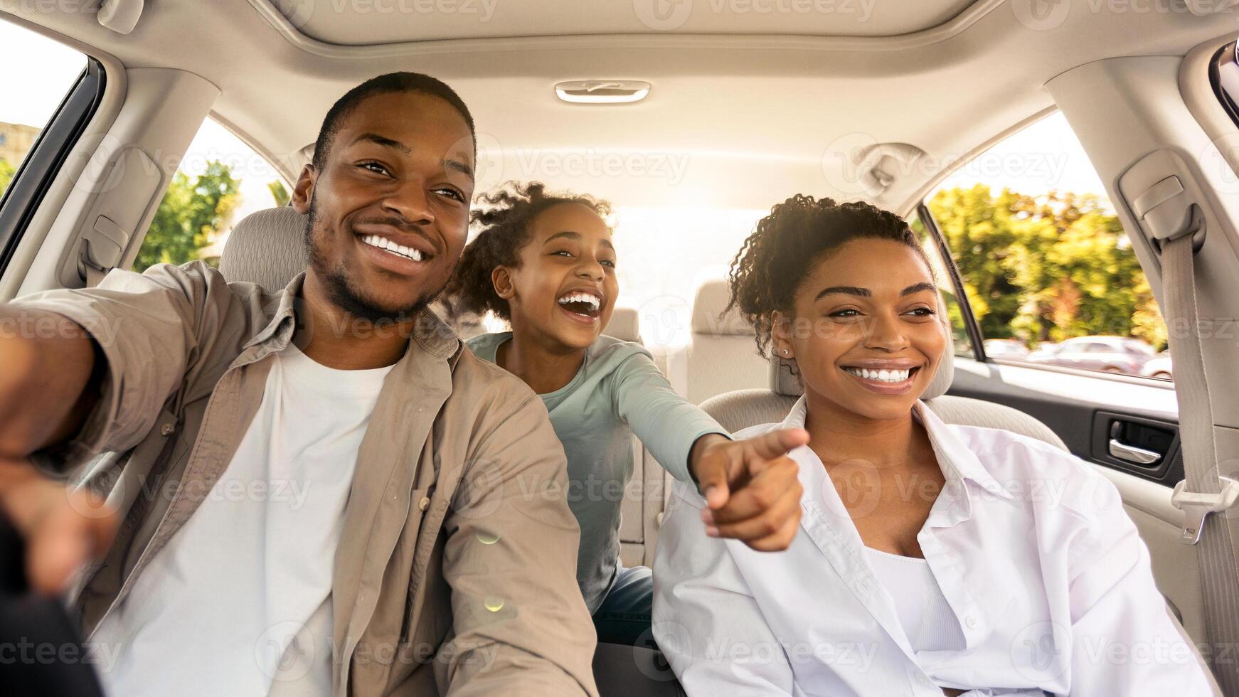 Auto Purchase. Joyful Black Family Having Road Trip Sitting In New Car Enjoying Summer Weekend Together. Parents And Daughter Riding Across City Traveling By Automobile. Selective Focus photo