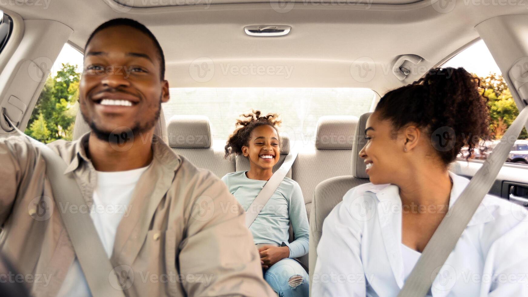 Joyful Black Family Driving New Car Having Ride In City. Parents And Daughter Sitting In Automobile Enjoying Road Trip On Vacation. Transportation Concept. Selective Focus photo
