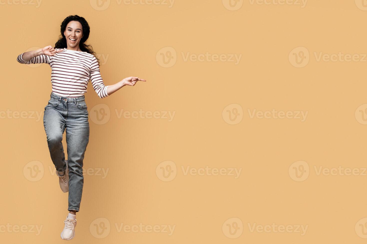 Cool Offer. Excited Joyful Arab Couple Jumping And Pointing In The Middle, Happy Cheerful Middle Eastern Man And Woman Showing Copy Space For Advertisement On Yellow Background, Full Length, Panorama photo