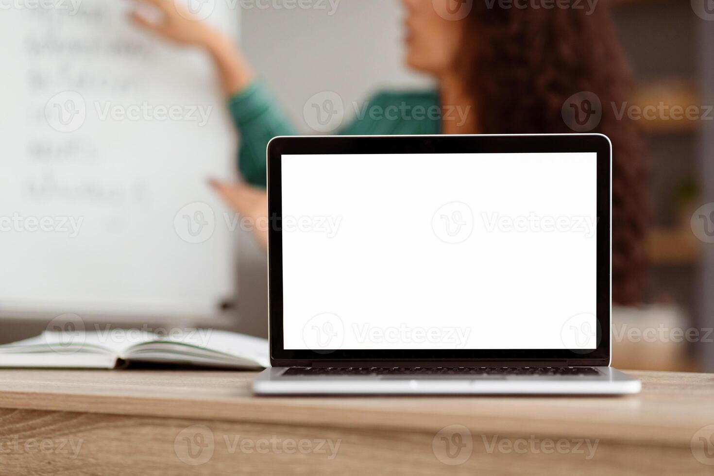 E-learning Course, Remote Education. Selective focus on blank white laptop screen on table, mock up. Lady teacher shooting lecture using computer having chat with students, explaining material photo