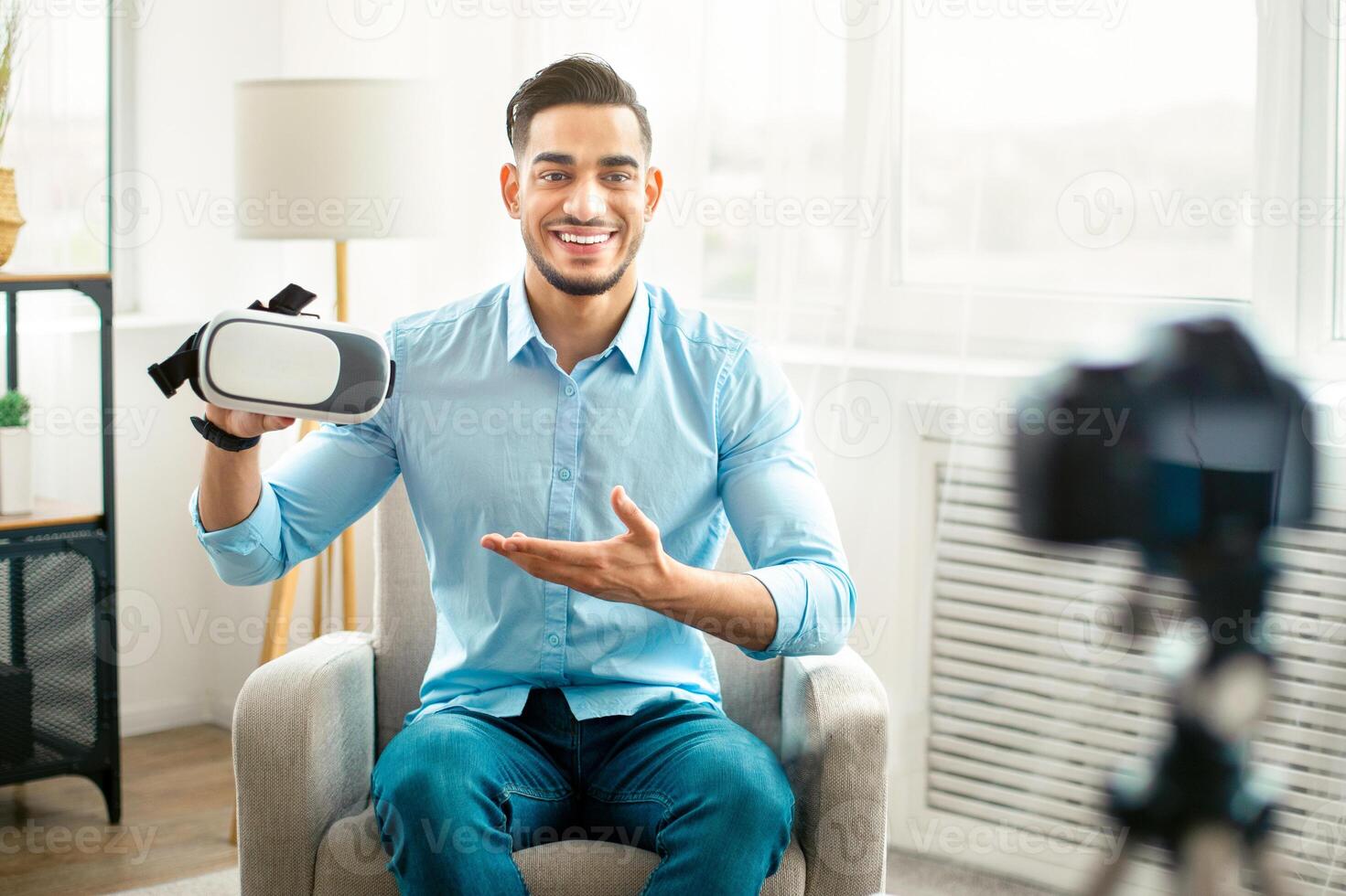 Arab guy vlogger making tech product review, presenting VR headset, shooting about cool device for technology blog at home. Eastern influencer recording brand advertising promo, using camera photo