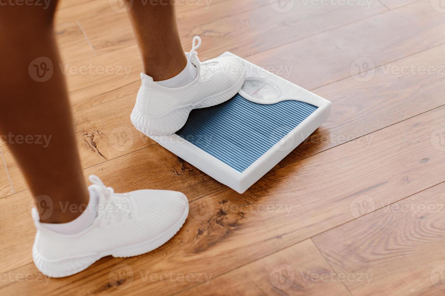 Healthcare And Body Weight Control Concept. Closeup view of young sporty woman stepping on bathroom scales indoors, checking her mass, cropped view of feet. Unrecognizable sporty lady on slimming diet photo