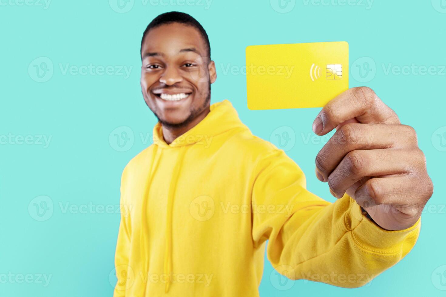 Cheerful African American Man Showing Credit Card Smiling To Camera Posing Standing On Blue Studio Background. Black Guy Advertising Bank Services. Selective Focus, Shallow Depth photo