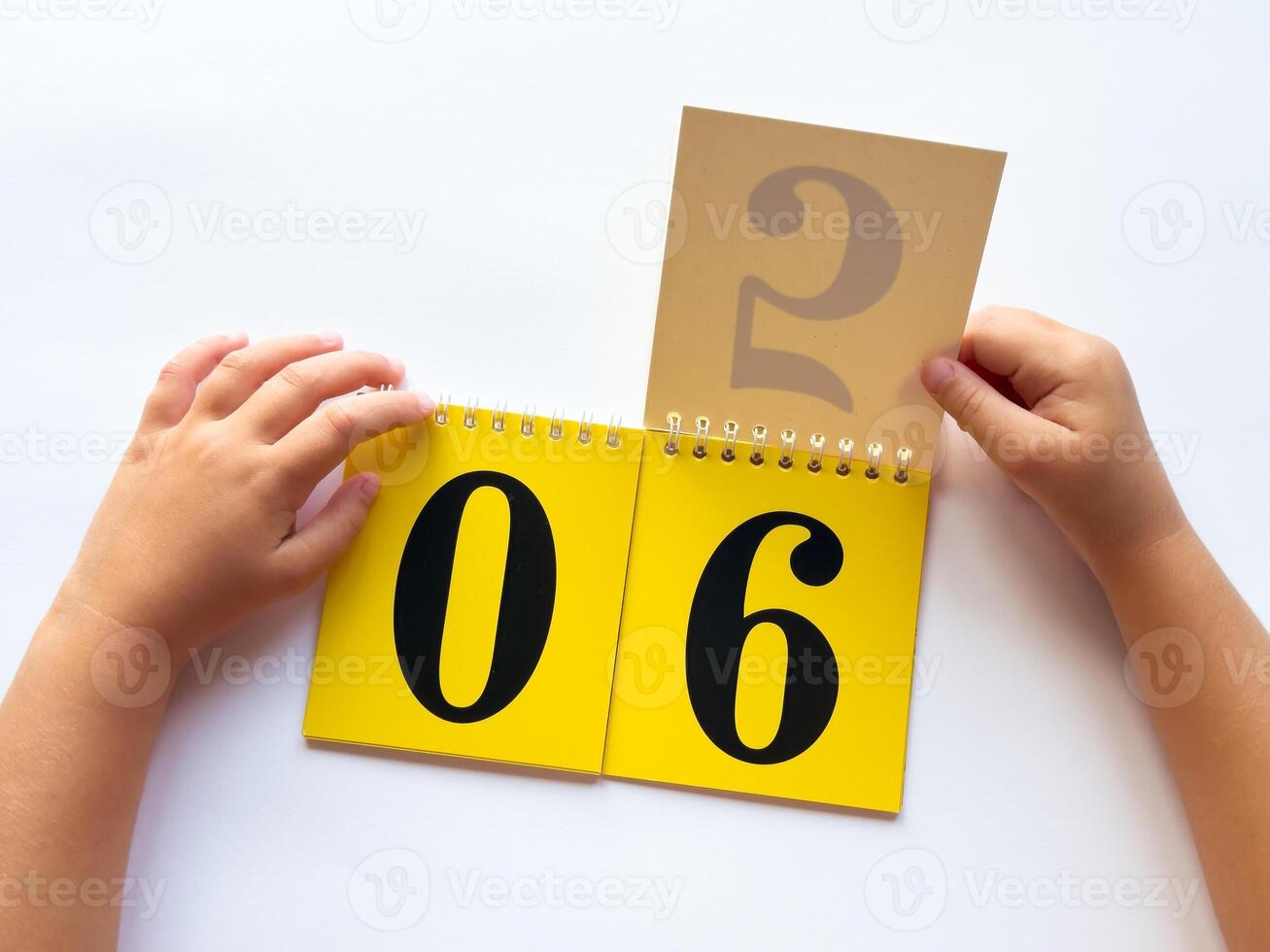 Child flipping calendar pages to change date on desk photo