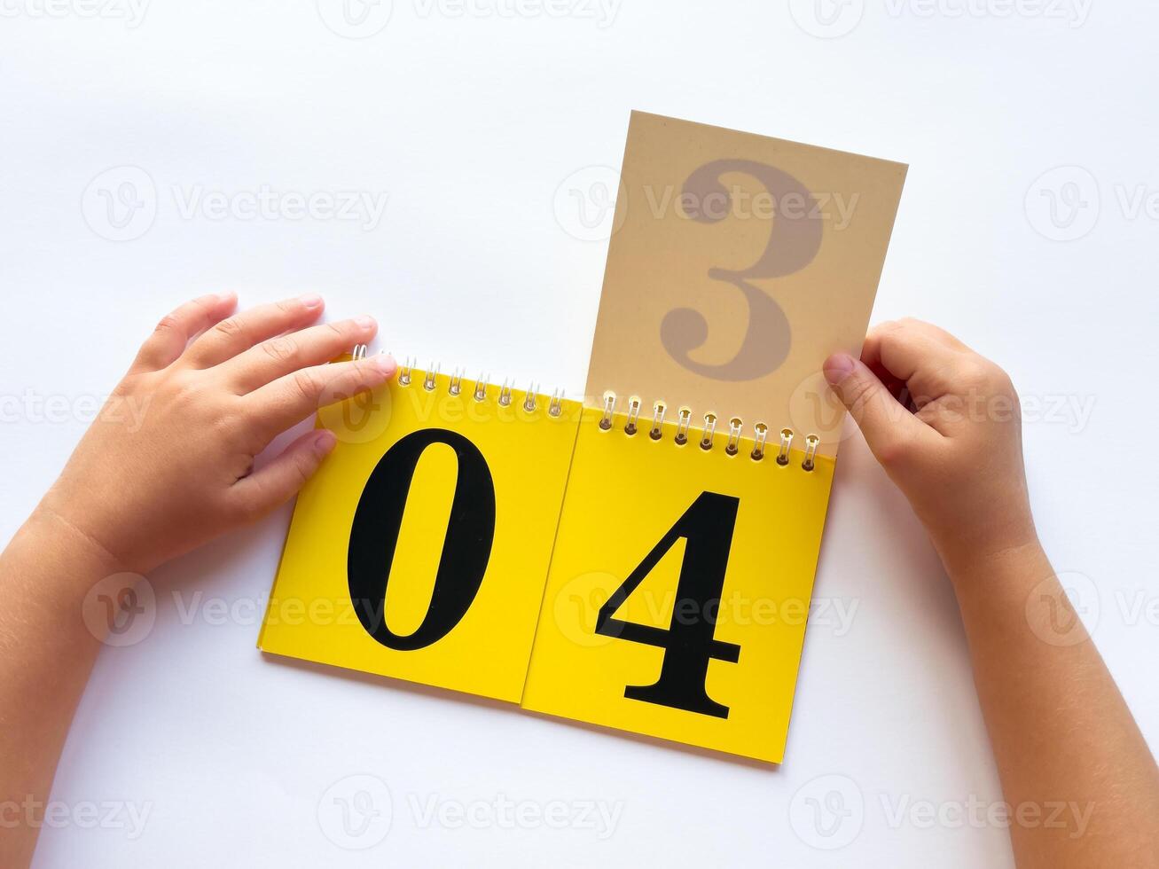 Childs hands turning pages on educational flip calendar with bold numbers photo