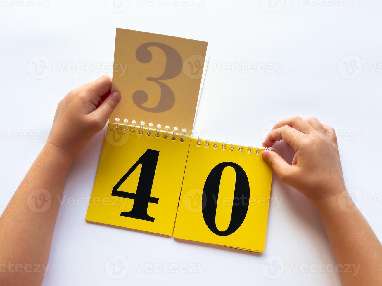 Childs hands flip through yellow pages with numbers on a white background photo