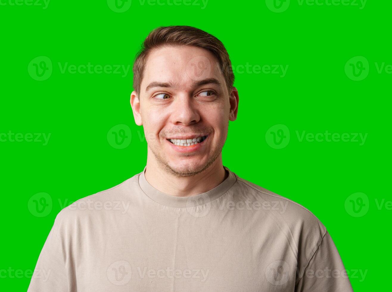 Smiling man in a beige shirt poses against a bright green background photo