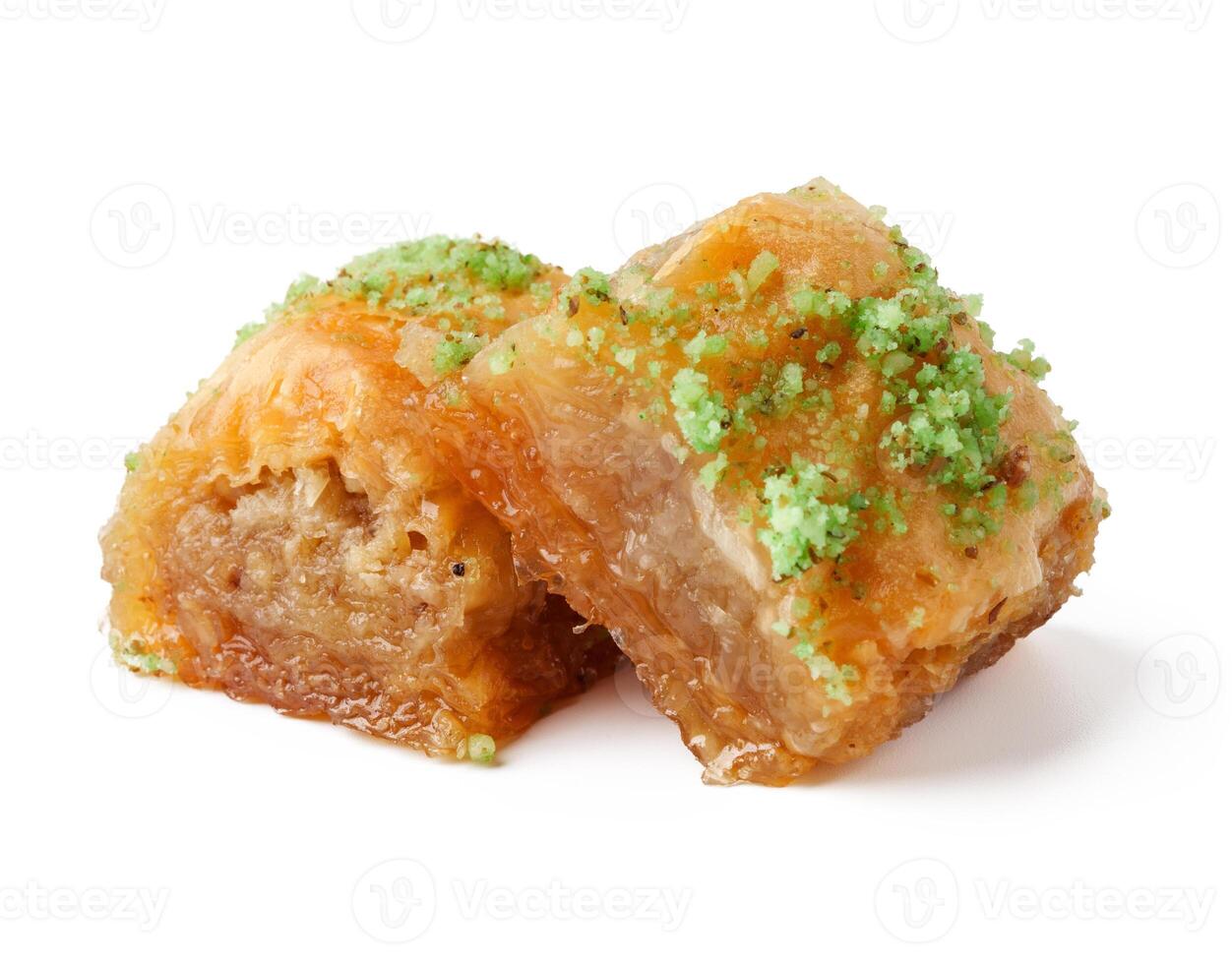 Delicious baklava filled with nuts and topped with green pistachios on a white plate photo