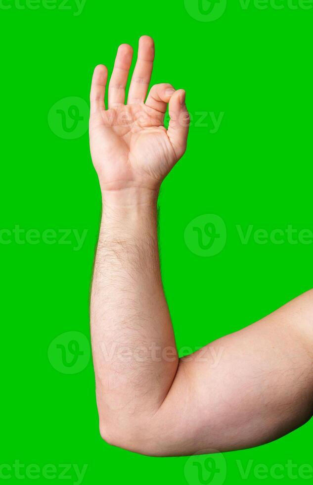 A hand making an okay gesture against a bright green background photo