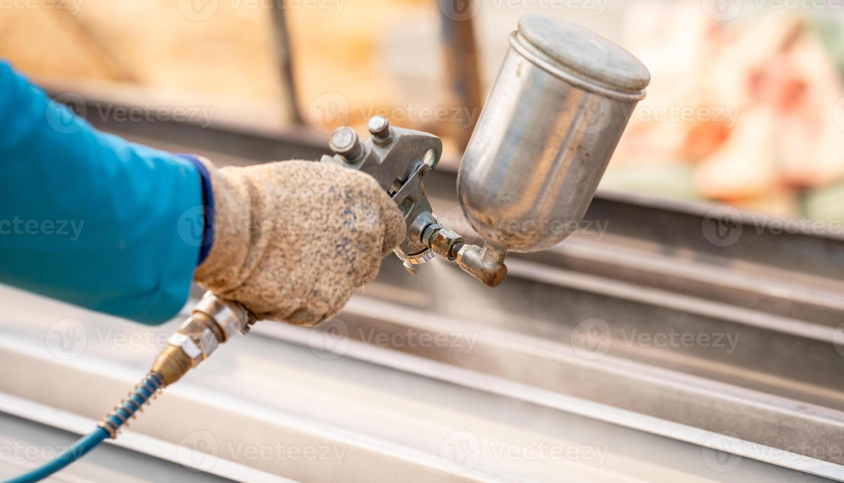 Construction worker painting metal structure surface coating with a spray gun at construction site. Metal corrosion and rust protection. Industrial precision. Protective coating to a metal structure. photo