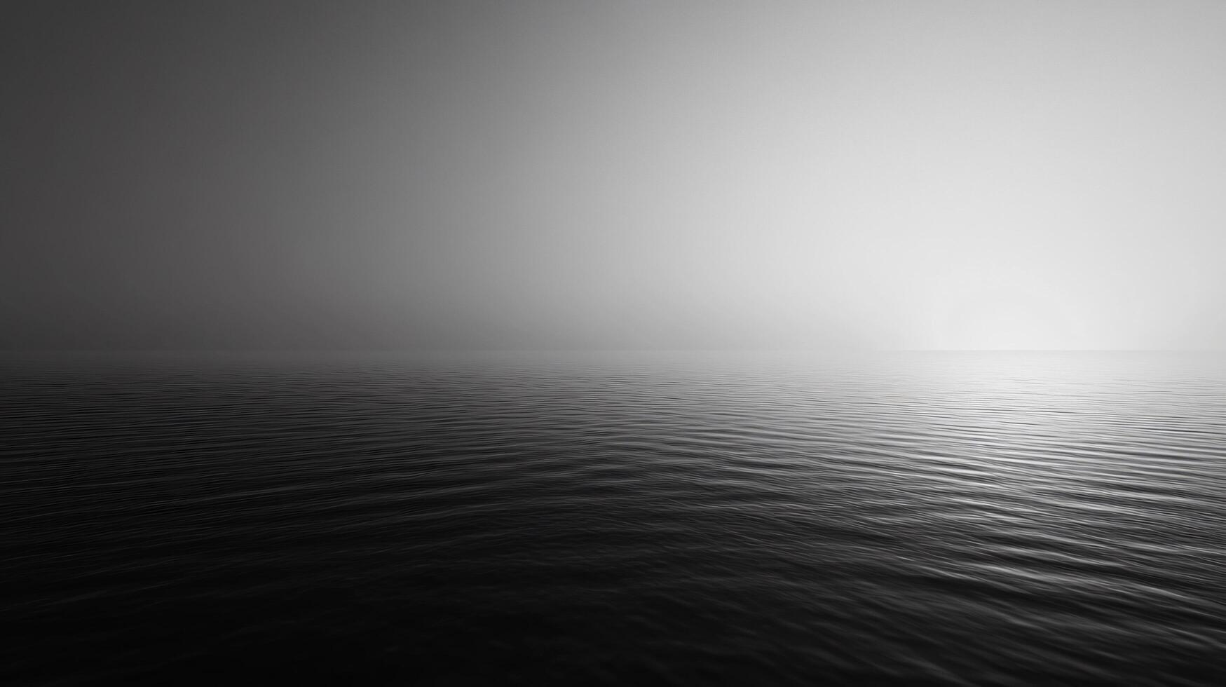 Minimalist black and white seascape featuring calm water with a light fog covering the horizon photo