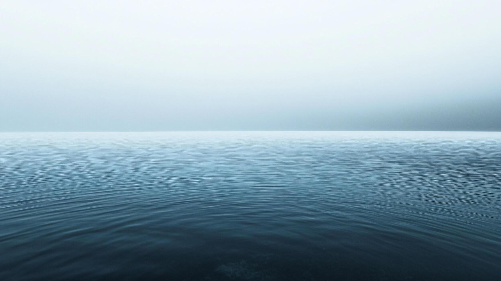 Minimalist landscape showing calm water surface merging with misty sky on a foggy day photo
