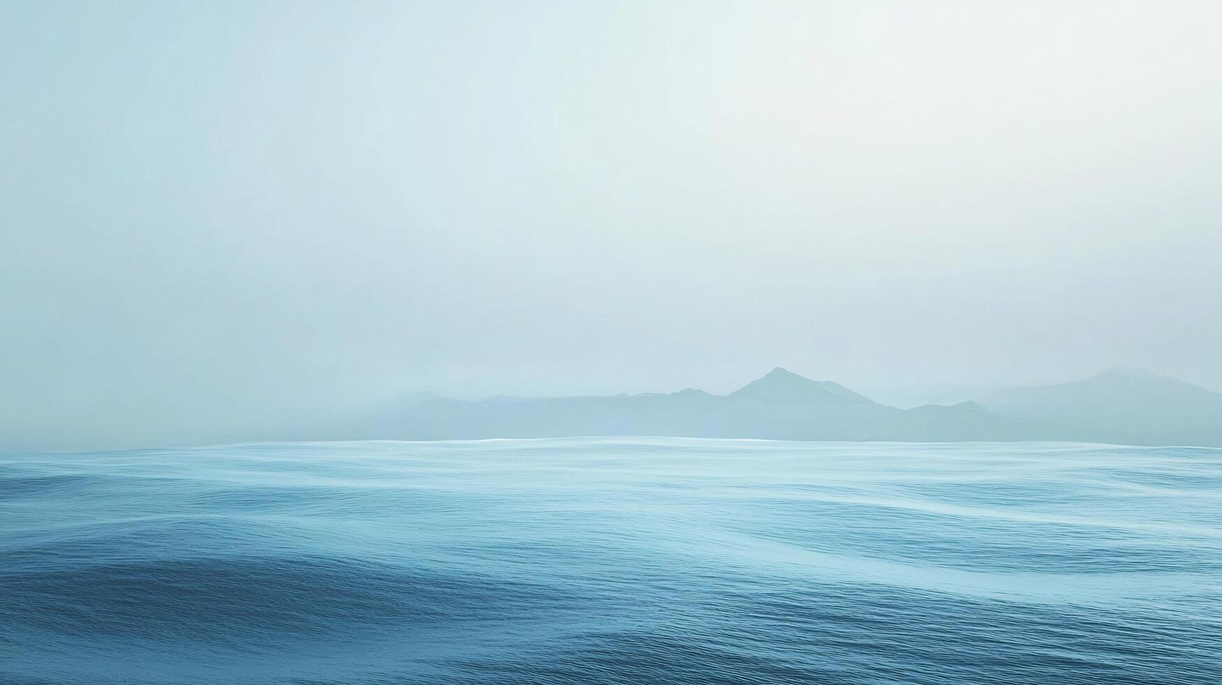 Calm ocean waves gently rolling towards a misty mountain range, creating a tranquil and minimalist seascape photo