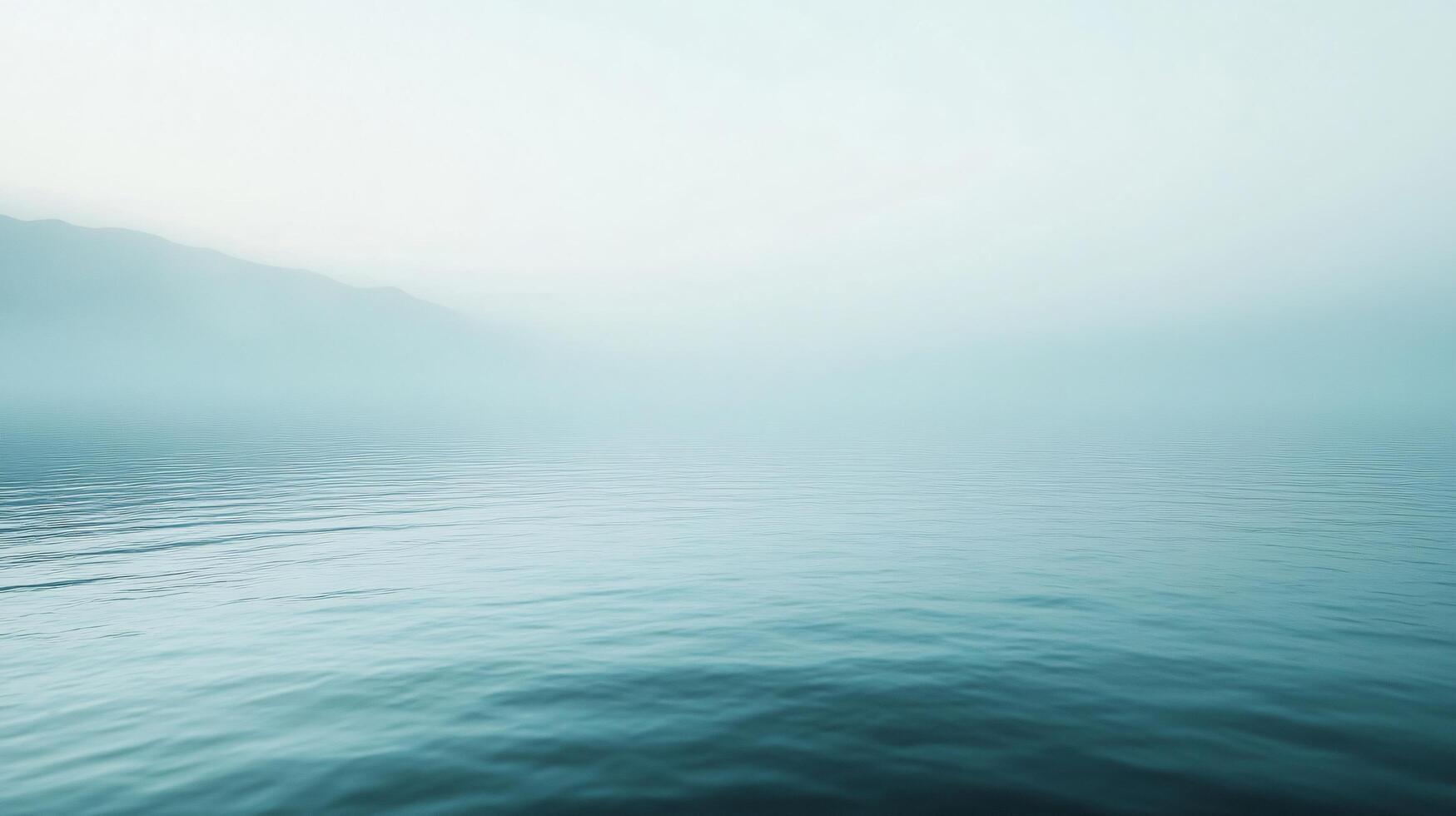 Minimalist landscape of a lake covered by fog at dawn with mountains in the background, creating a serene and peaceful atmosphere photo