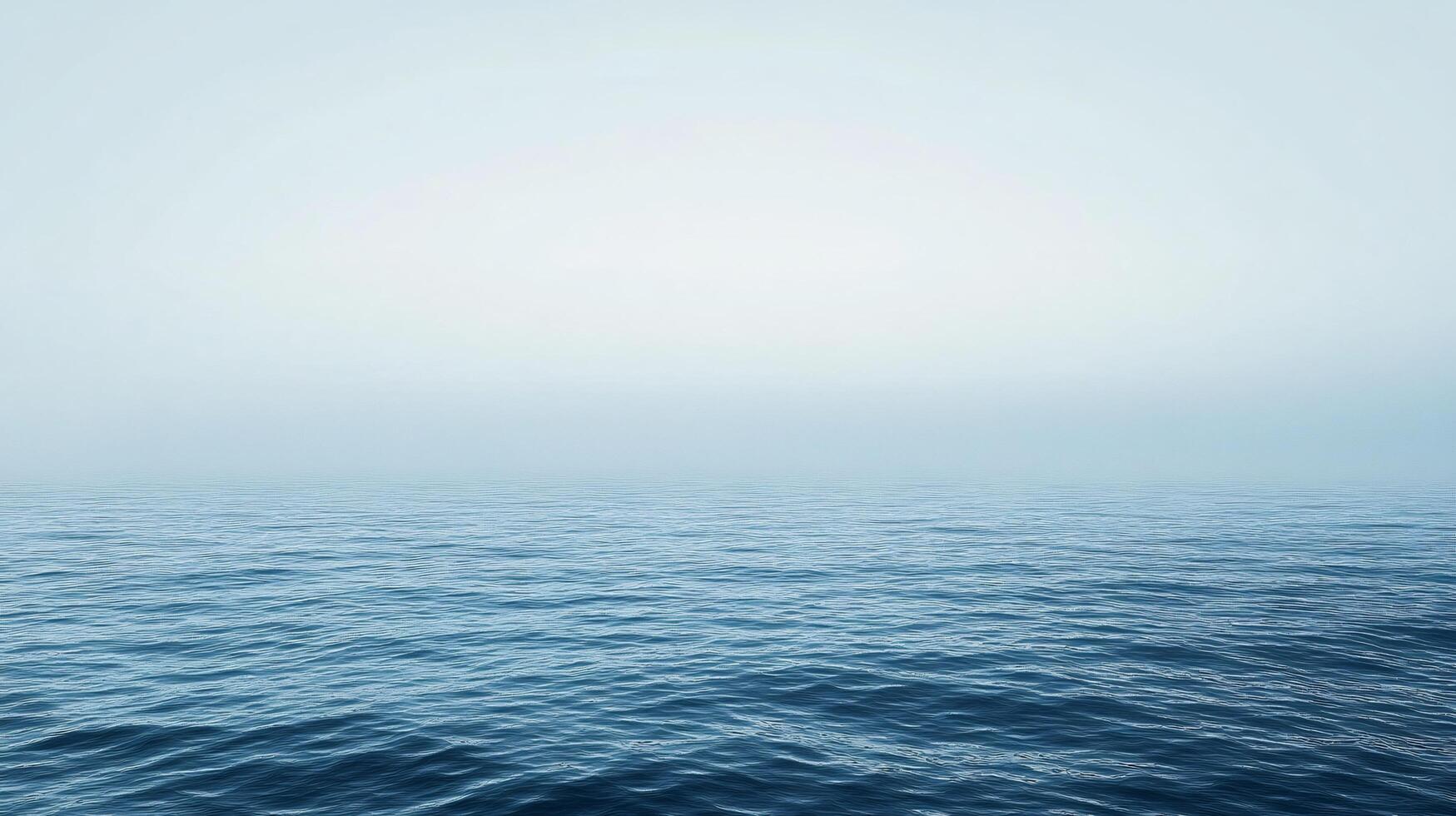 Tranquil blue ocean surface merging seamlessly with a misty sky, creating a serene and minimalist seascape photo