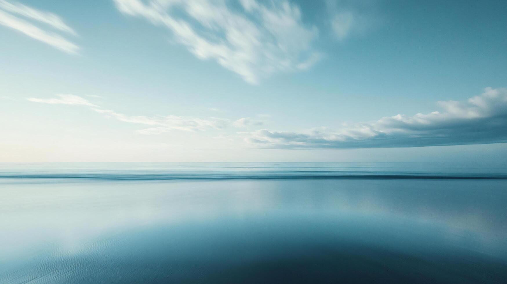 Minimalist seascape featuring calm ocean reflecting cloudy sky during long exposure photo