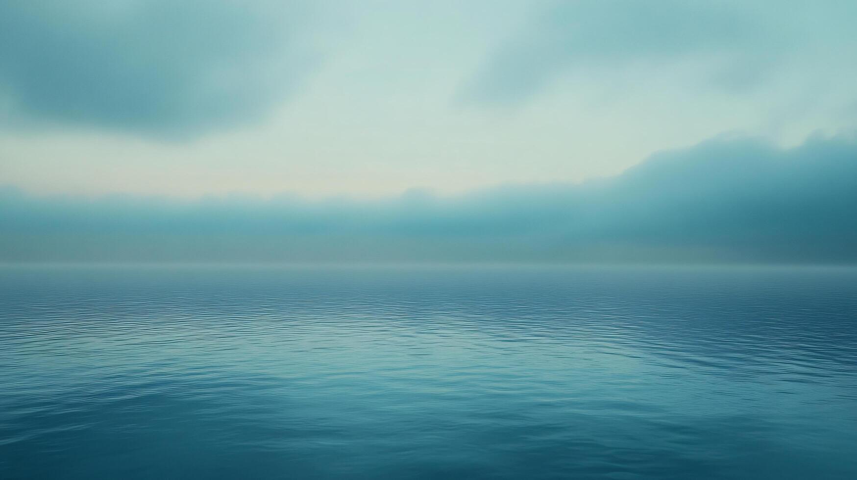 Calm ocean water reflecting a cloudy sky during a misty sunrise, creating a serene and tranquil atmosphere photo