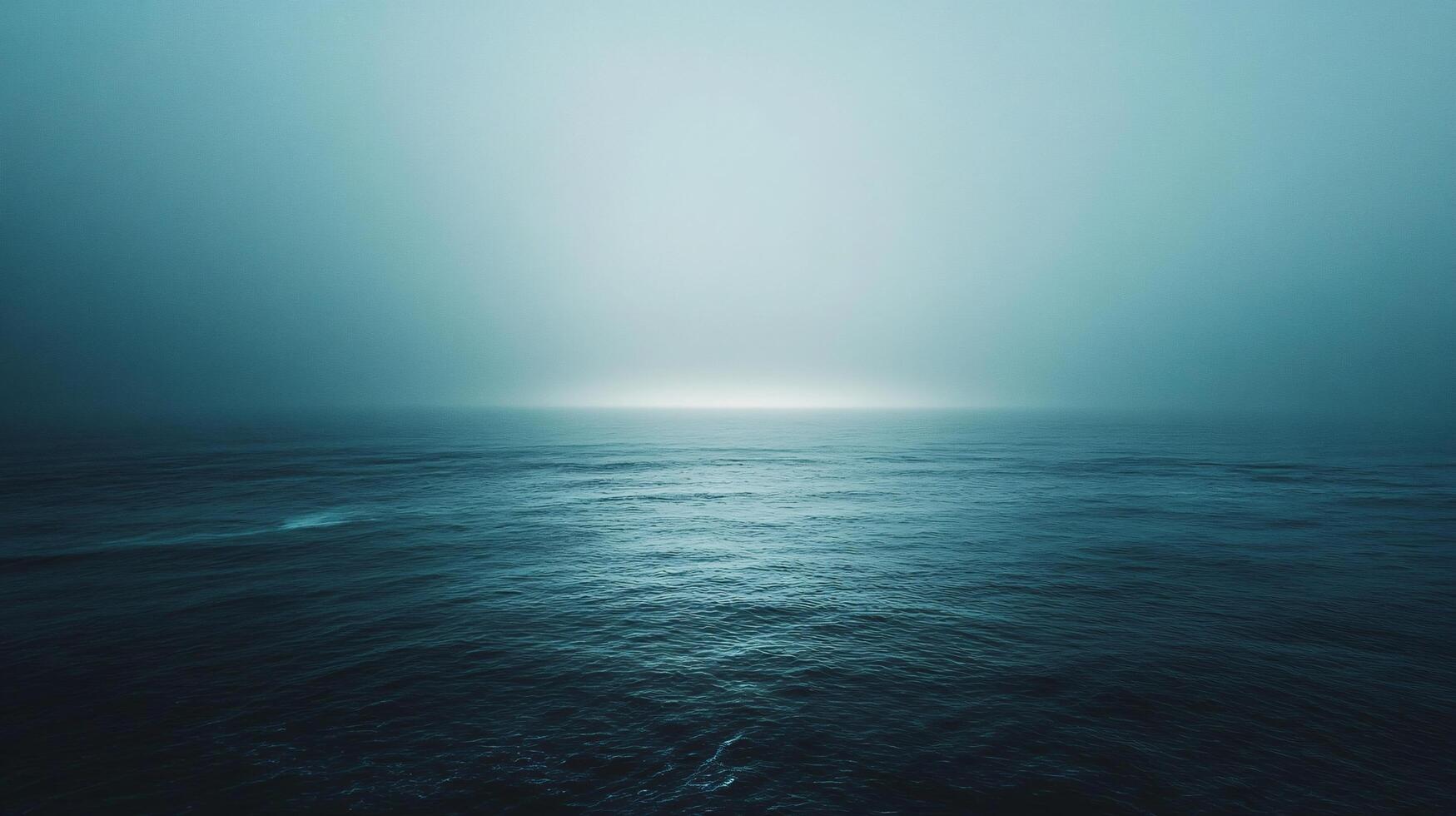 Ethereal light piercing through thick fog creates a mystical atmosphere over a tranquil dark ocean photo