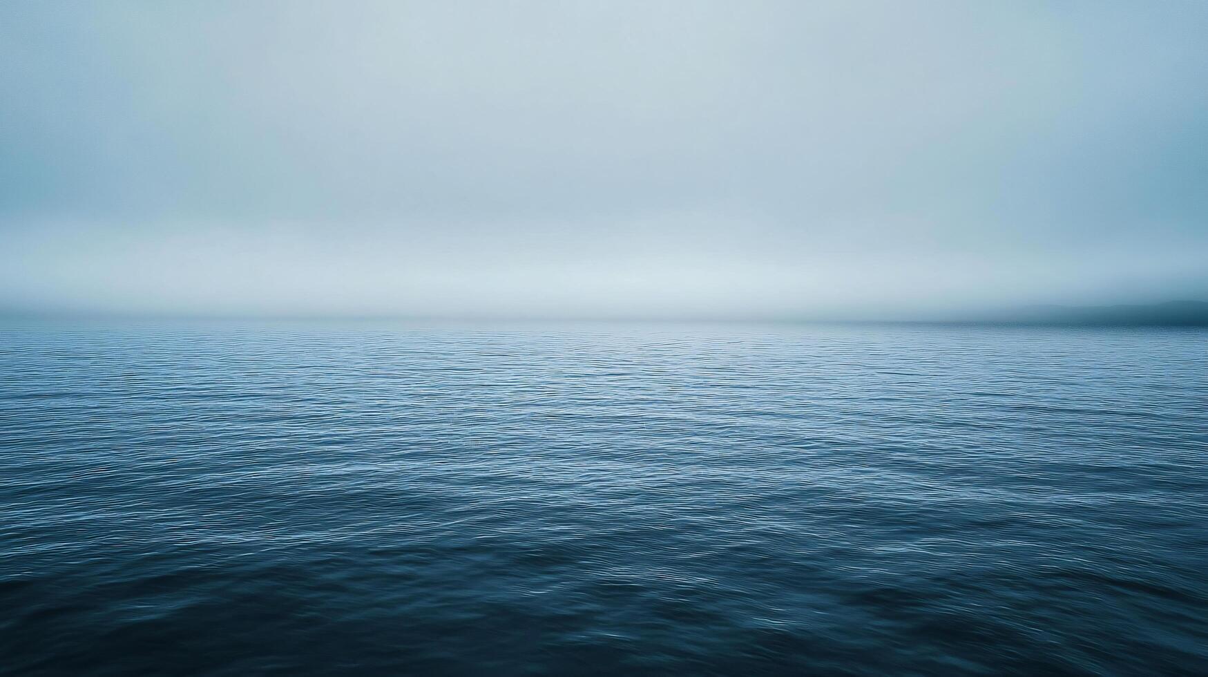 Calm ocean waters blend seamlessly with a misty sky, creating a tranquil and minimalist seascape photo