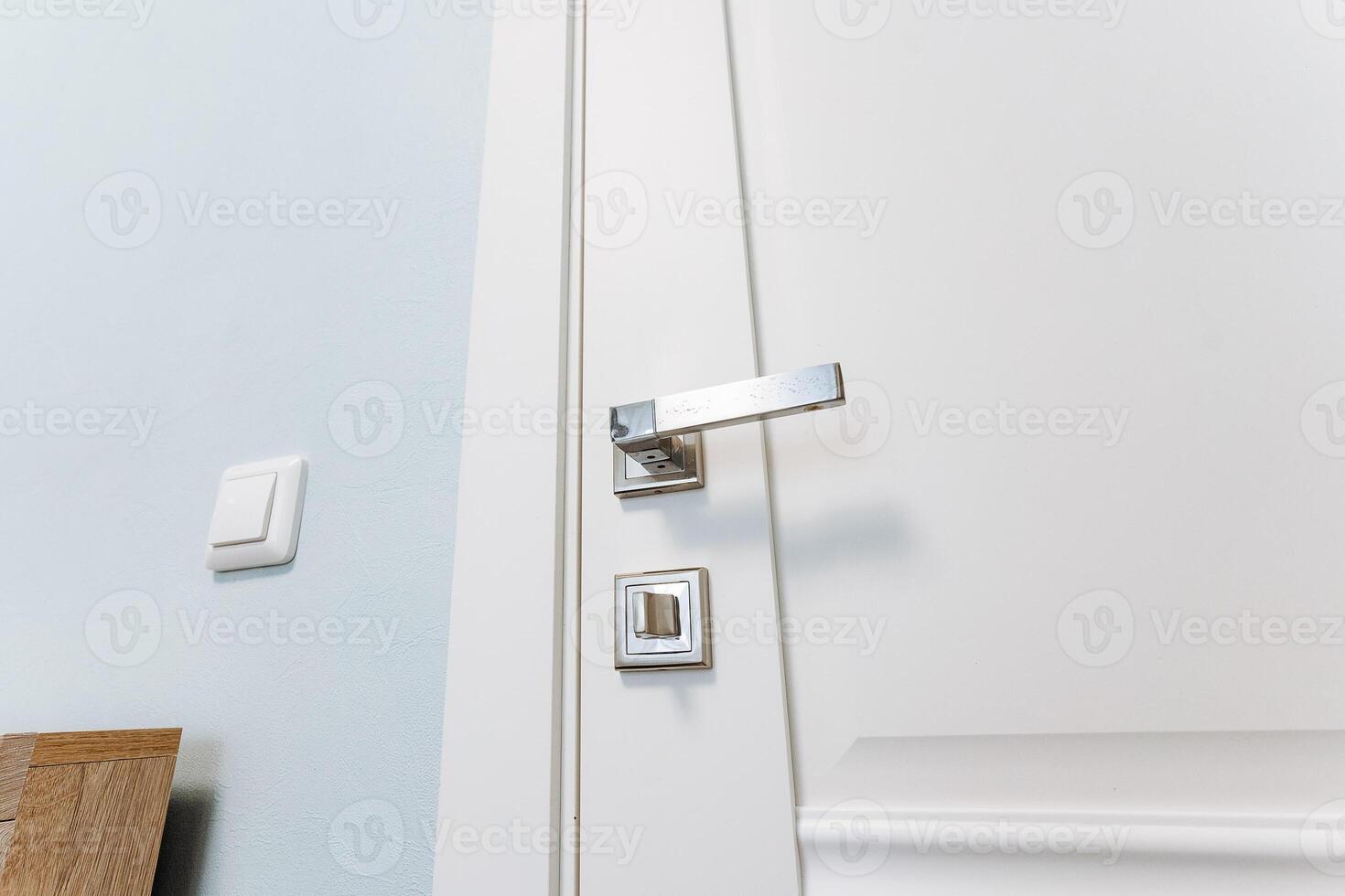 Close-up shot of a white door with a sleek chrome handle fixture photo