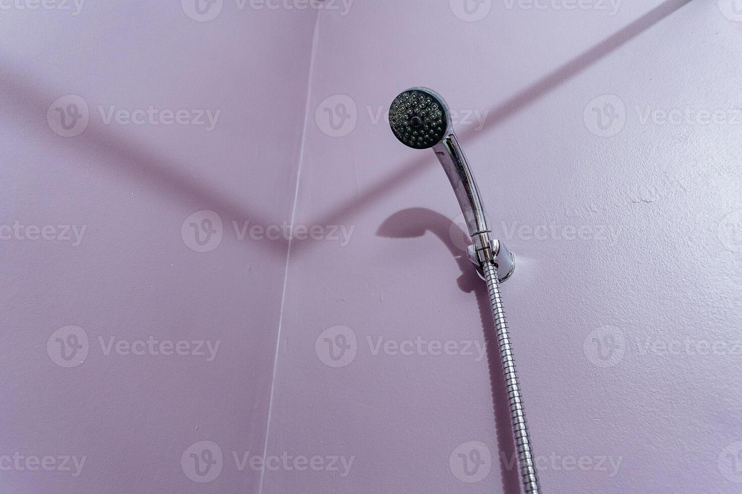 a shower head is hanging on a pink wall in a bathroom photo