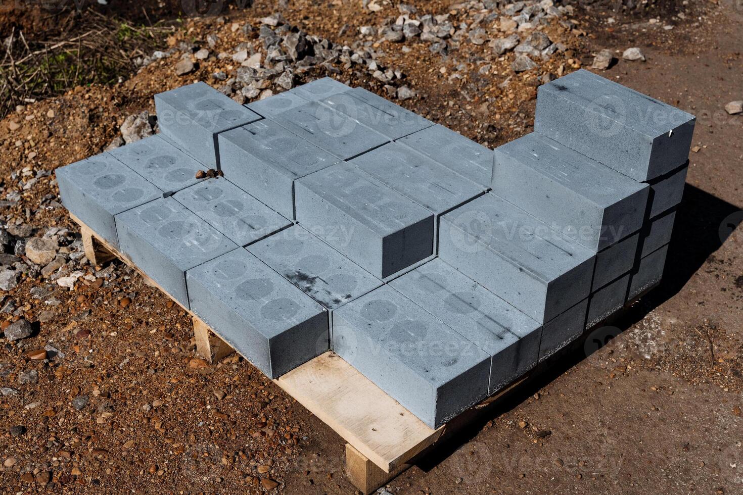 A pile of gray concrete blocks stacked on a pallet at a construction site for building. These durable and solid materials are essential for the projects foundation and structural support photo