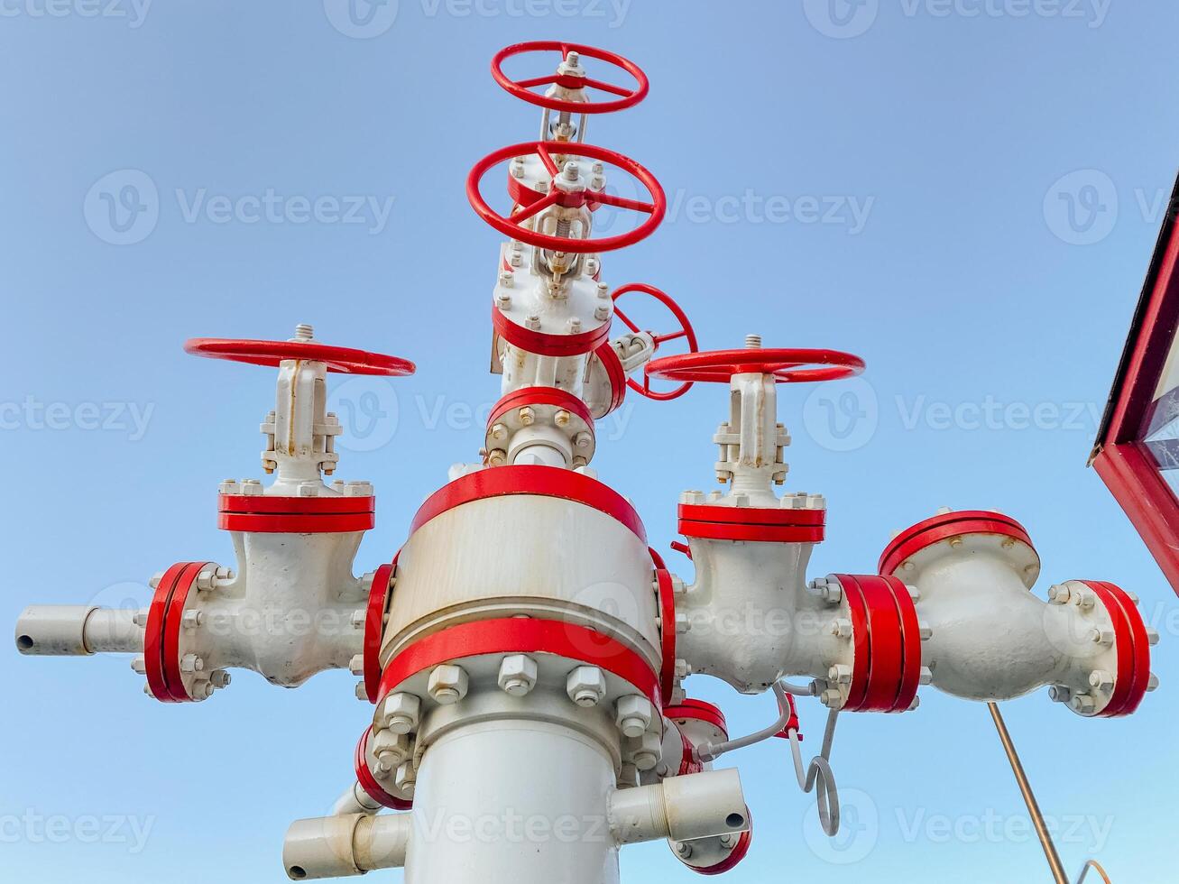 A white pipe featuring red valves can be seen prominently against a vast blue sky, presenting a contrast of colors and elements that evoke a sense of engineering and utility photo