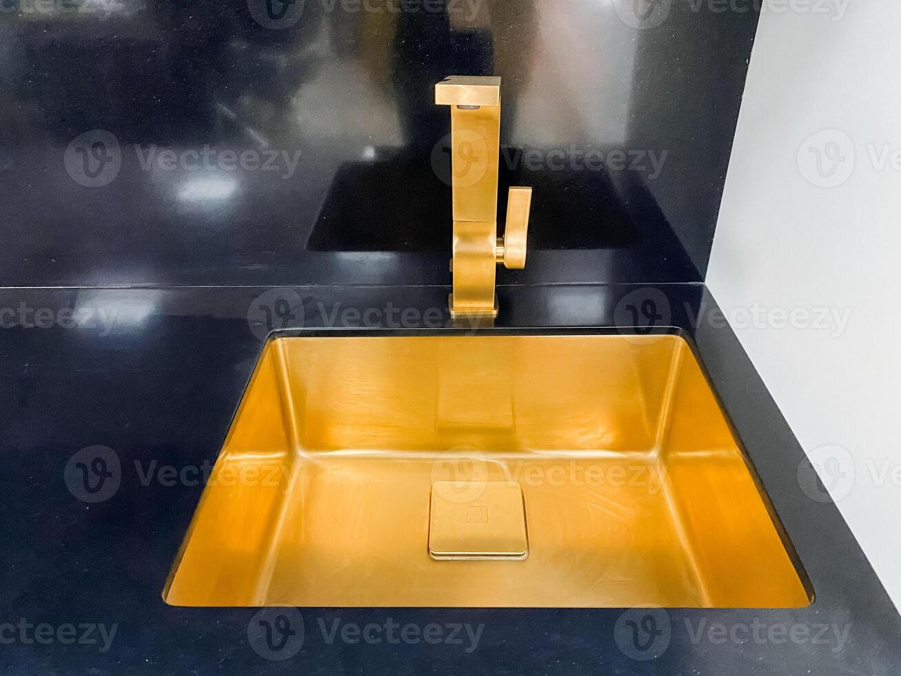 The gold sink elevates the rooms aesthetic, pairing elegantly with a modern black countertop and ornate gold faucet, creating a stunning visual appeal for all who enter photo