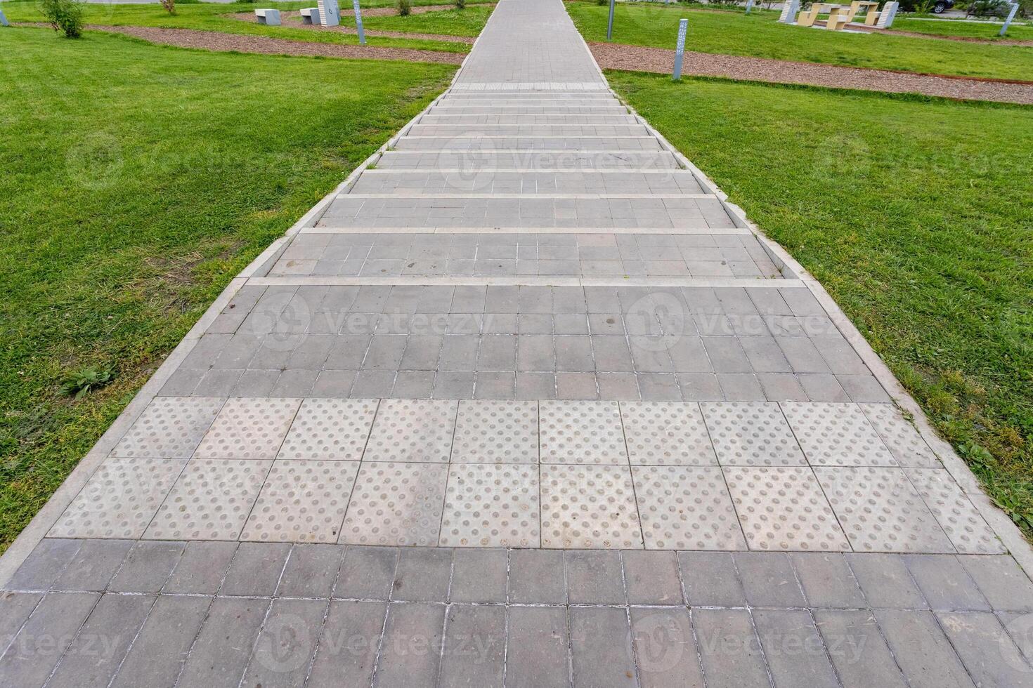 A beautiful brick walkway that leads to a grassy area in a lovely park photo