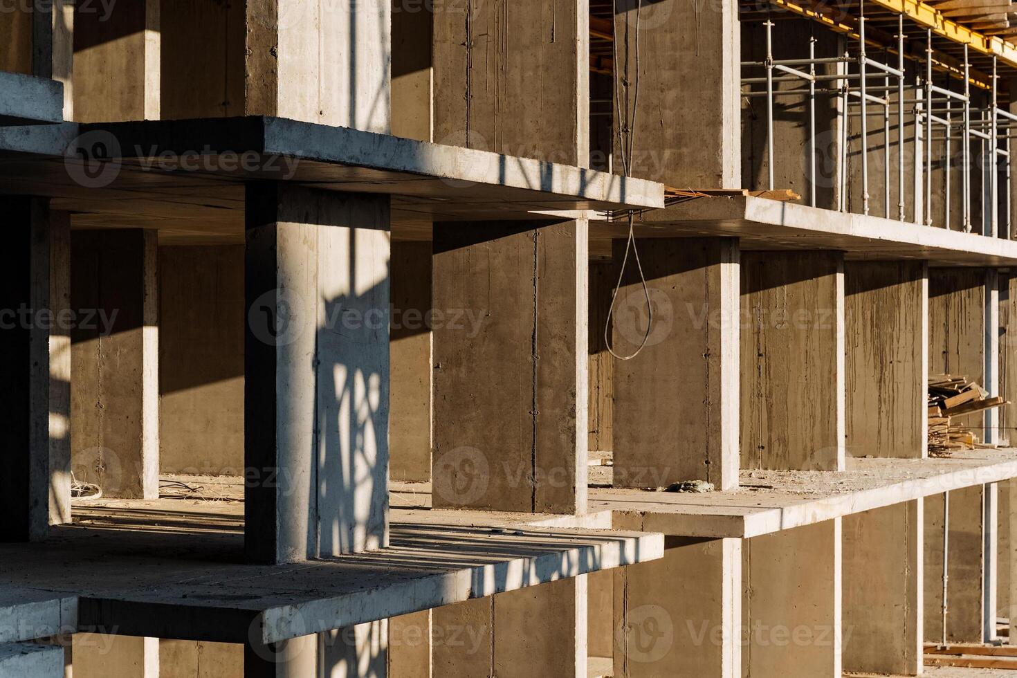 A large building is currently under construction, featuring sturdy concrete pillars and extensive scaffolding for support during the ongoing work process to complete the structure photo