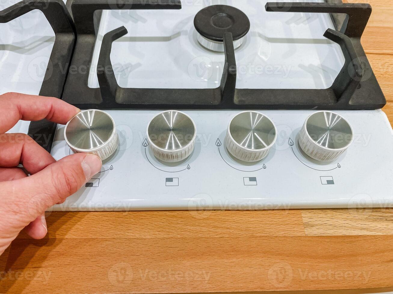 A person is carefully adjusting the knobs on a gas stove, ensuring that the flame levels are just right for cooking. This action reflects their attention to culinary detail and precision photo