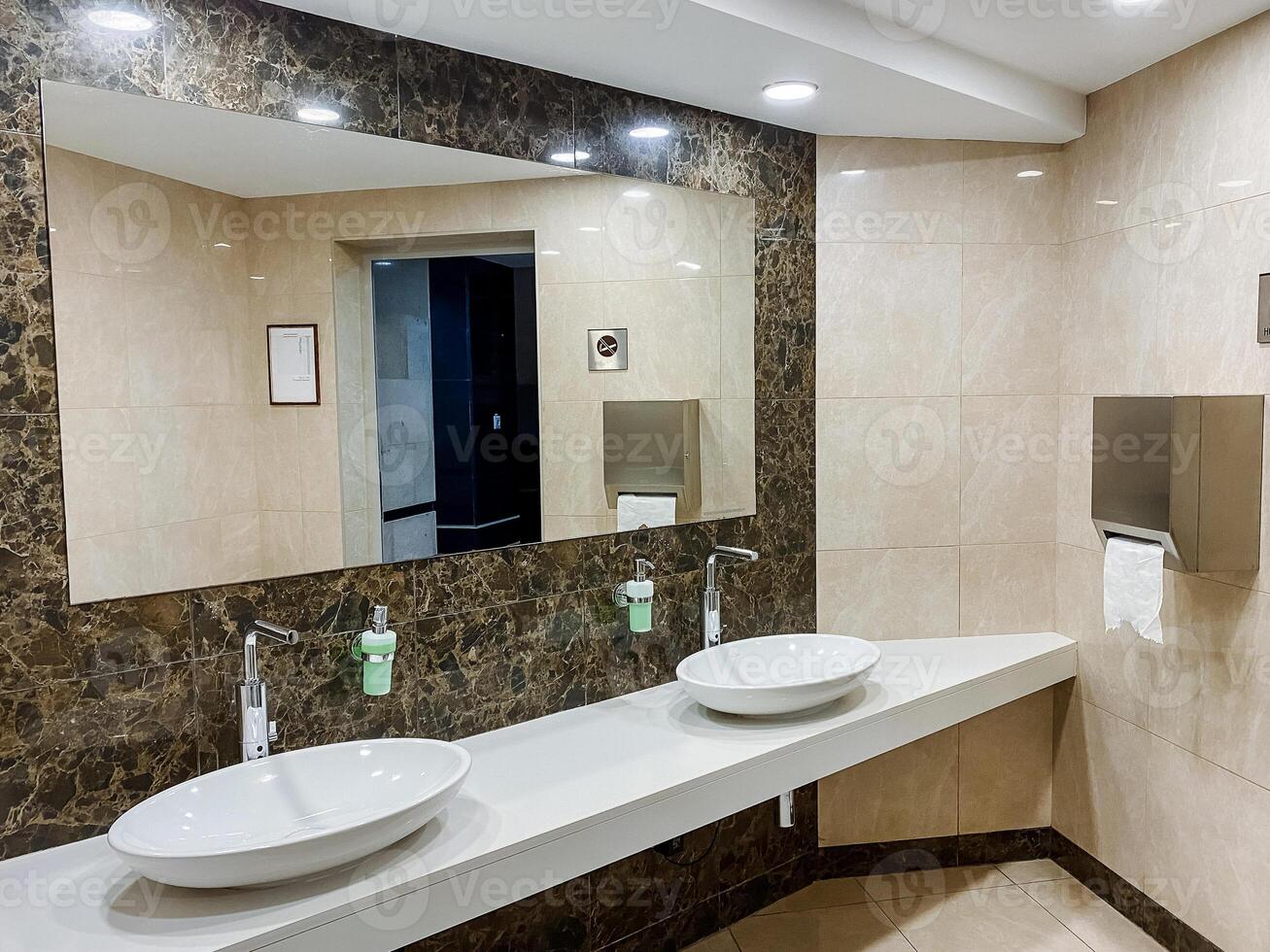 Property with wood wall, twin sink fixture, spacious mirror and interior design photo
