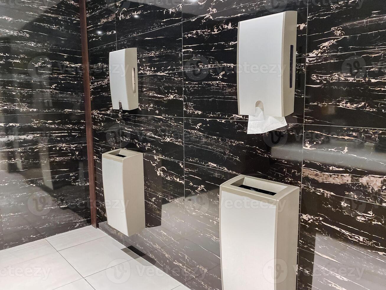 A building with a clean restroom equipped with urinals, trash can, hardwood flooring, window, and a real estate facade. photo